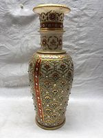 Full view of the marble vase showing its tall shape, floral pattern, and decorative stones.