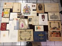 Top-down view of multiple royal-related documents, cards, certificates, and booklets arranged on a grid surface.