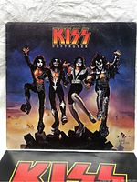 Front cover of Kiss Destroyer vinyl album showing band members illustrated in jumping pose against colorful sky background.