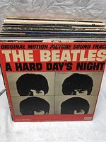 Front cover of The Beatles A Hard Day's Night original soundtrack album showing black and white image of band members with red and cream colored text.