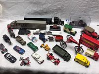 Full lot overview showing a variety of diecast cars, motorcycles, trucks, wagons, and buses arranged on a white surface.