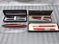 Lot showing four sets of pens and pencils including two pen sets in cases and loose pen and pencil.