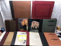 Lot of nine vintage record albums and folders arranged, showing variety of colors and titles, including classical music pieces and record labels.