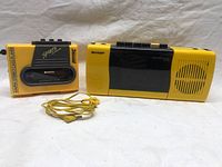Pair of yellow AM/FM cassette radios shown side by side, with yellow earbuds in front.