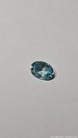 Oval cut lagoon blue natural Cambodian zircon gemstone shown against plain background, highlighting cut and clarity.