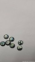 Seven small round faceted tricoloured sapphires on plain background showing their color and clarity