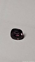 Close up photo of a cushion cut purple spinel gemstone showing its color and cut