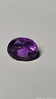 Close-up image of the 1.81ct oval cut purple amethyst gemstone showing its faceted surface and deep purple color.