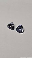 Two trillion cut tanzanite gemstones on neutral background showing color and clarity.