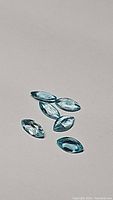 Six marquis cut paraiba blue apatite gemstones arranged on a neutral surface to show color and clarity.