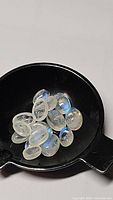 Close-up of a group of smooth polished oval cabochon rainbow moonstones showing bright blue flashes under light.