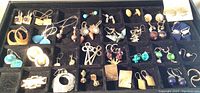 Tray showing 29 pairs of assorted earrings, various shapes, sizes and colors including blue, gold, silver, multicolored glass beads and metal designs.