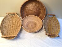 Four unique baskets; two ovals with wooden handles, two round baskets including one with a geometric pattern