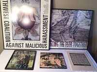 Two large framed posters from Northwest Coalition Against Malicious Harassment, one from 10th annual conference and one from 11th, with a collage of historical moments and art pieces on the table below.