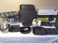 Overview of full bakeware set including muffin pans, Bundt mold, roasting pan with rack, two stainless steel mixing bowls, immersion blender, and hand mixer.