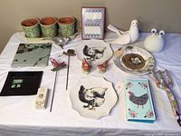 Full lot including ceramic plates, salt & pepper shakers, small pots, garden stakes, porcelain bird figurine, nightlight, wall art, decorative tiles, box, wallet, and gardening rake.