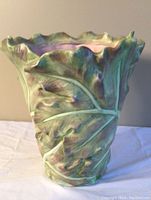 Front and side view of a tall ceramic cabbage leaf vase with detailed leaf texture and green coloration