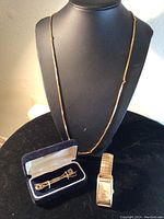 Gold-tone Lord Elgin wristwatch, Nordstrom tie clips in box, and gold-tone necklace on display bust.