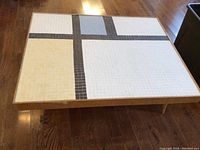 Top view of rectangular coffee table showing mosaic tile design with sections in white, cream, blue and dark gray tiles.