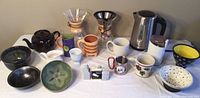 Full lot overview showing mugs, bowls, carafes, teapot, and kitchen accessories arranged on a table