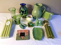 Full view of the complete set showing all glass, ceramic pieces, candles, and decorative items arranged on a table with a beige wall background.