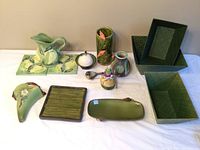 Full lot of olive-themed ceramic decorative pieces, baskets, and trays displayed on white cloth.