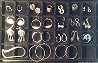 Photo displaying 18 pairs of earrings in various styles from hoops to dangles with turquoise and coral accents, and the bracelet and rings included in the lot visible.