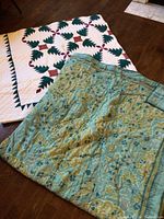 Christmas-themed quilt with green pine tree pattern on white background, visible on bed.