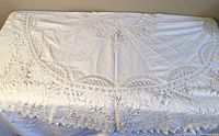 Top view of the folded rectangular ecru tablecloth showing scalloped lace edges and fine fabric detail