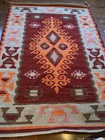 Full view of colorful geometric patterned rug lying on floor.