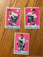 Front view of three 1970-71 O-Pee-Chee Vancouver Canucks hockey cards showing players Rosaire Paiement, Dale Tallon, and Andre Boudrias.