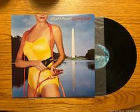 Front cover of the 'What's Funk?' vinyl album showing woman in yellow suit with jumper cables and Washington Monument background, with the vinyl record partially out of the sleeve.
