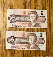 Front side of two Canadian $2 bills from 1986 with Queen Elizabeth II portrait