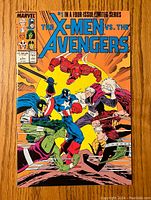 Front cover of The X-Men vs. The Avengers #1 comic showing main characters Wolverine, Hulk, Captain America, Iron Man, Quicksilver, and Scarlet Witch fighting on an intense orange background.