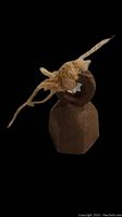 antique miniature sheep bell with hexagonal rusted metal body and beige cord tied on top loop on a black background