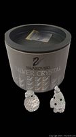 Photo showing the two Swarovski Silver Crystal mini figurines, a penguin and a dog, along with the original round branded box and documentation inside the box lid.