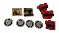 Two red vintage View-Master viewers, four vintage circular slide reels with black edges, and two cardboard covers for slide reels labeled Las Vegas and Queen's Coronation.