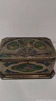 Front and top view showing detailed painted scenes on lid and front panel of tin.