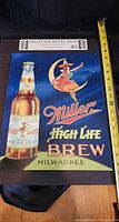 Full view of 18 inch metal tin sign featuring Miller High Life Brew advertising with bottle image and crescent moon woman graphic.
