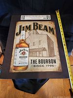 18-inch metal Jim Beam bourbon collector metal tin sign with a bottle image and distillery background.