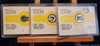 Three vintage hockey NHL insert ring cards from 1973-74 in plastic sleeves, front showing colorful team logos of Cleveland Barons, Pittsburgh Penguins, and Philadelphia Flyers.