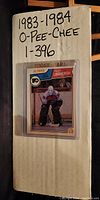 Cardboard cover with handwritten “1983-1984 O-Pee-Chee 1-396” and a sample plastic-sleeved card