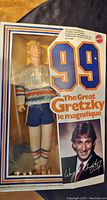 Front view of the Mattel Wayne Gretzky figure in original sealed box showing the figure in Oilers gear and signature graphics on the packaging.