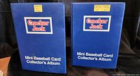 Two blue Mini Baseball Card Collector's Albums labeled Cracker Jack from 1991 and 1992, standing side by side for scale and identification.