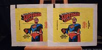 Front view of two yellow Superman trading card wrappers featuring classic Superman comic art, logos, and text indicating 5¢ price and TV show reference.