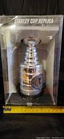 Front view of Stanley Cup replica in clear plastic packaging with visible championship medallion