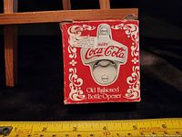 Front view of the Coca-Cola bottle opener original box showing branding and vintage style with minor wear and tears.