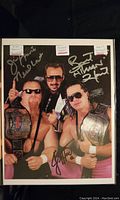 Full view of autographed photo showing Bret Hart, Jim Neidhart, and Jimmy Hart