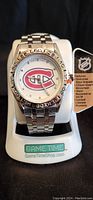 Men's Montreal Canadiens watch front view showing the logo on the dial, stainless steel bracelet, and attached product tag.
