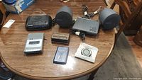 Photo of the entire lot showing the Panasonic radio alarm clock, Spartus alarm clock, Yamaha stereo receiver and speakers, RCA cassette player, Sharp electronic address book, and an electronic compass